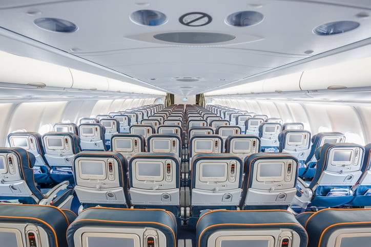 View from back of airplane interior with blue seats and orange headrests