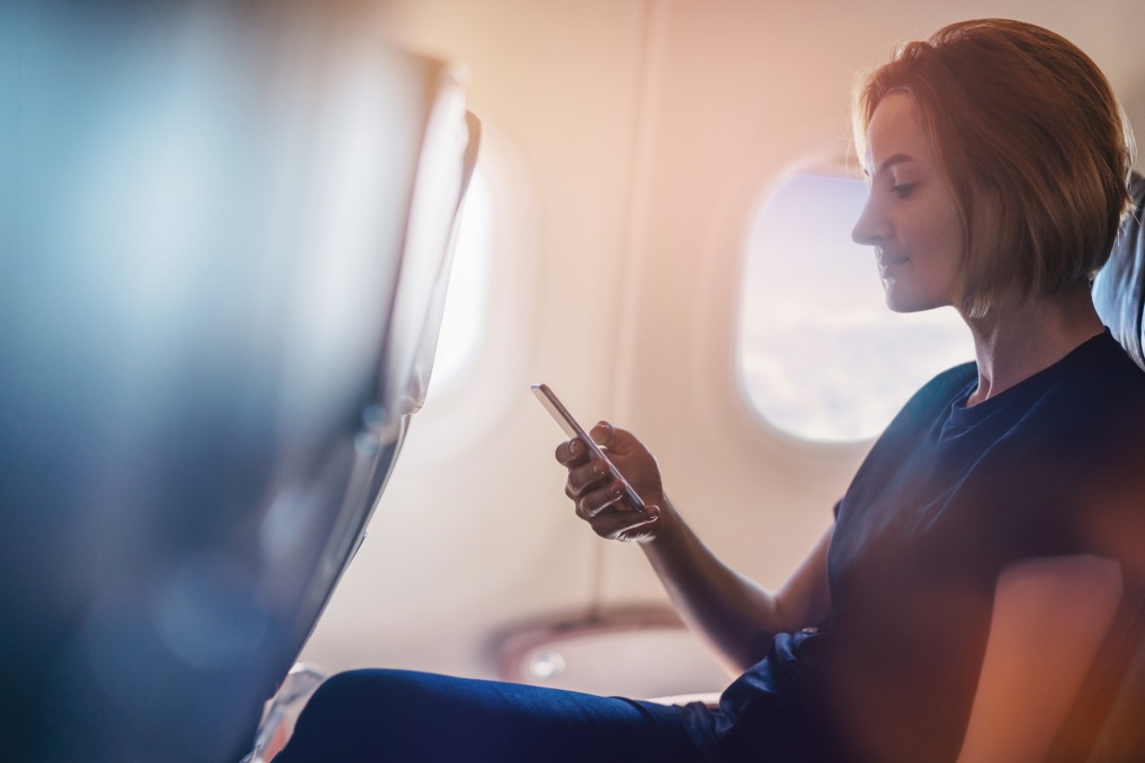 Woman looking at smart phone on aircraft