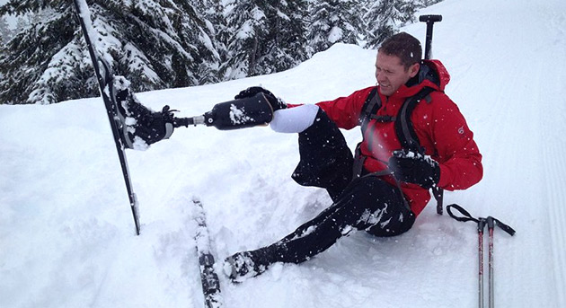 Peter Bowker adjusting his skis and artificial leg