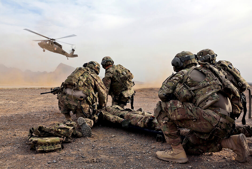 Group of soldiers performing an evacuation with a medical helicopter coming into land