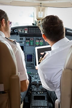 Pilot And Copilot Using Digital Tablet In Cockpit
