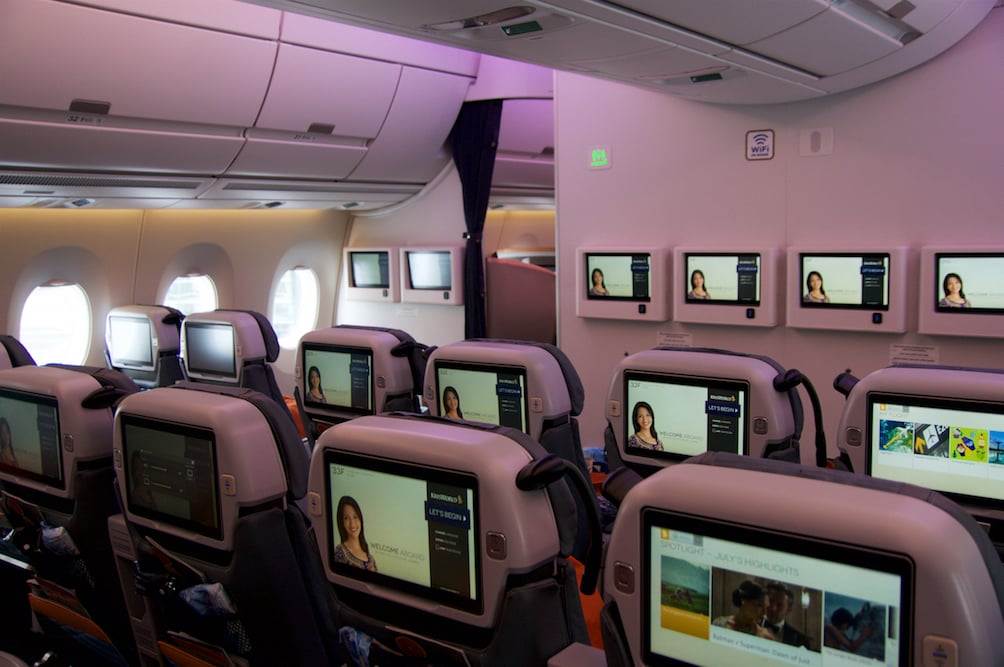 Looking across a widebody aircraft cabin with seatback screens on
