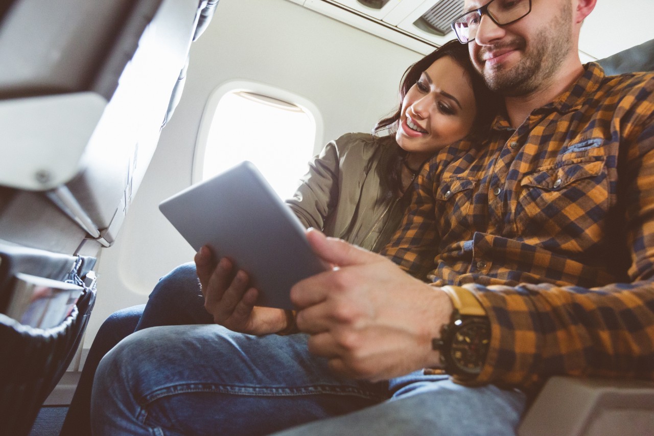 Couple traveling by plane using tablet pc.