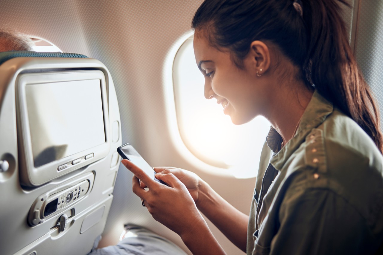 Young woman using her smartphone onboard an aircraft