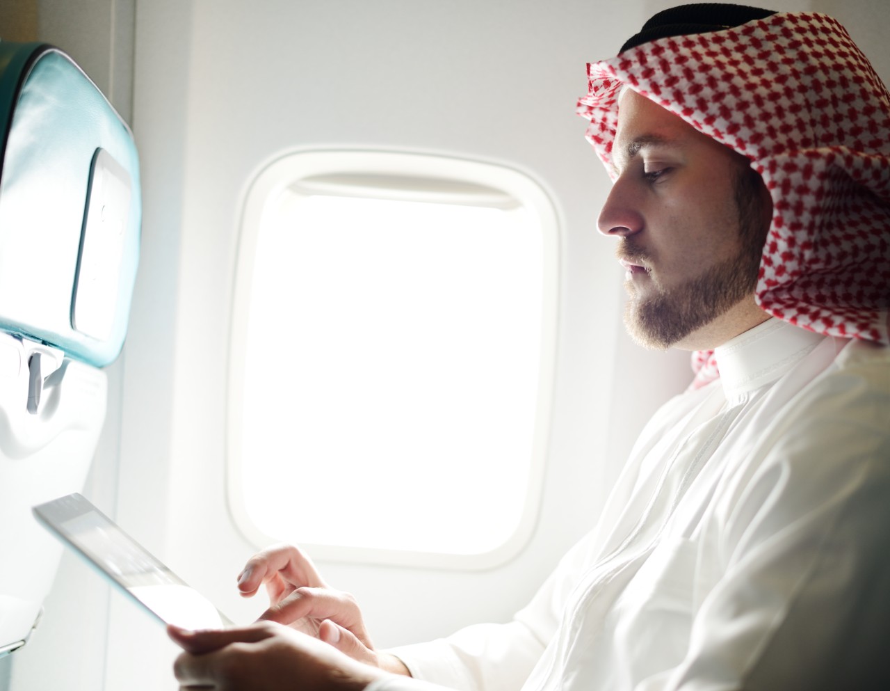 Arabic businessman working on tablet computer on aircraft