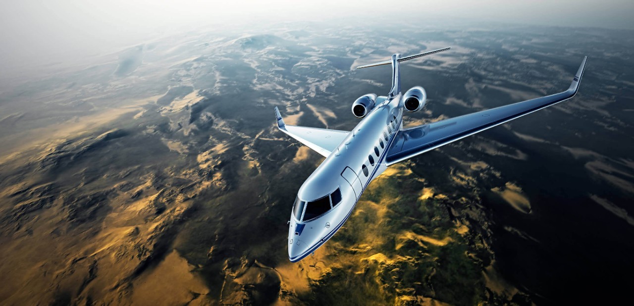 Silver business jet flying over a mountain range