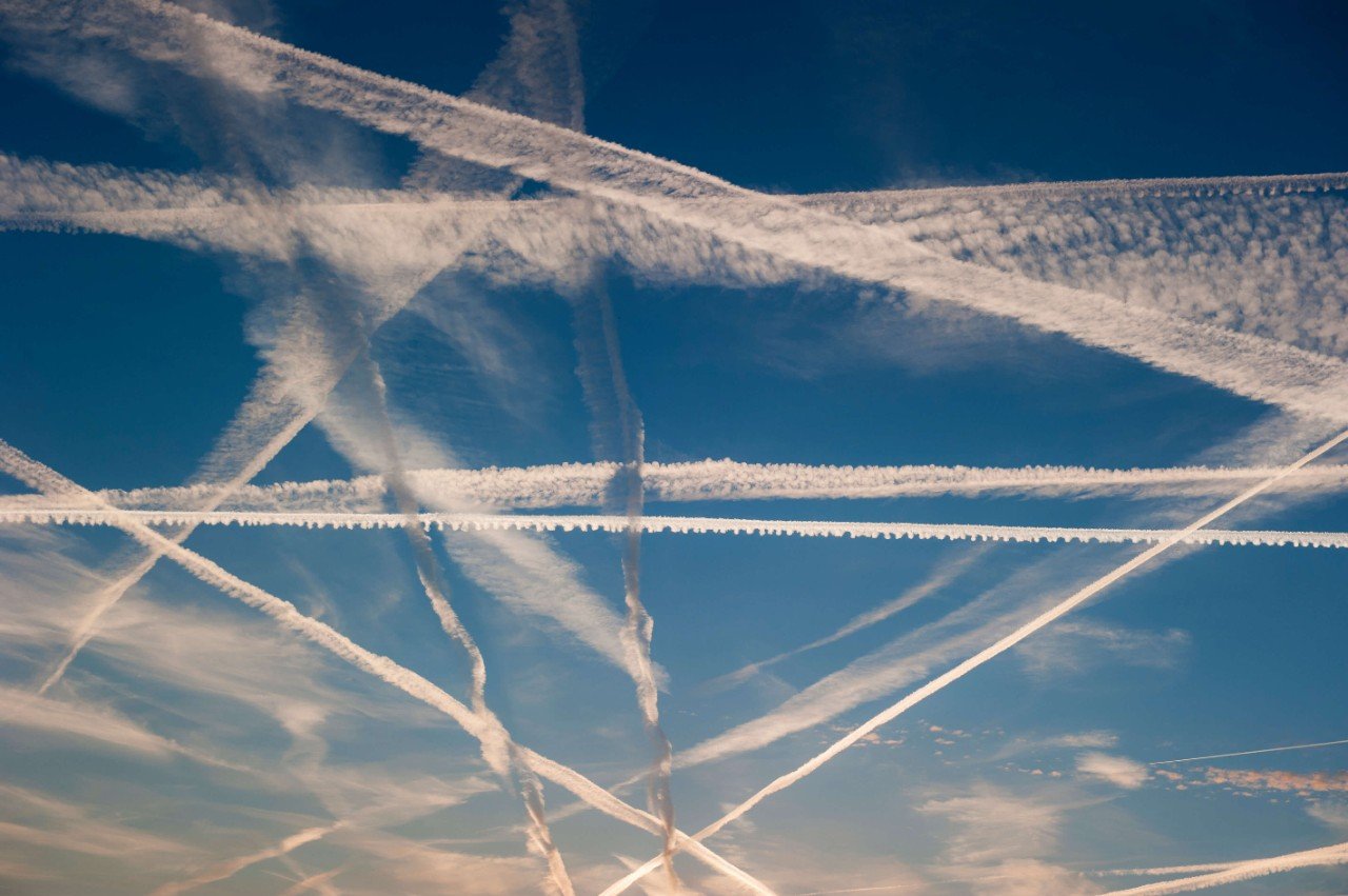 Pattern of airplane trails of condensed air crisscrossing each other against the blue sky