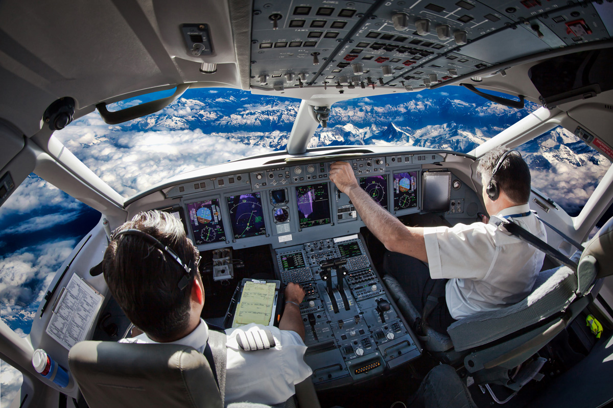 Pilots navigate over mountainous terrain in a modern airliner cockpit