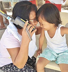 A mother and child using a satphone provided by Inmarsat to make a call