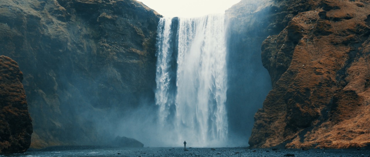 Woman overlooking waterfall at Skógafoss, Iceland. 