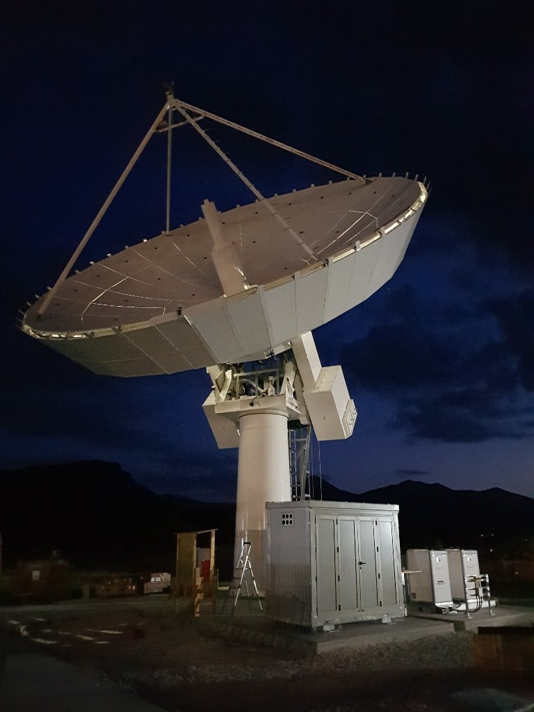 Large antenna dish against night sky at satellite ground station in Nemea, Greece