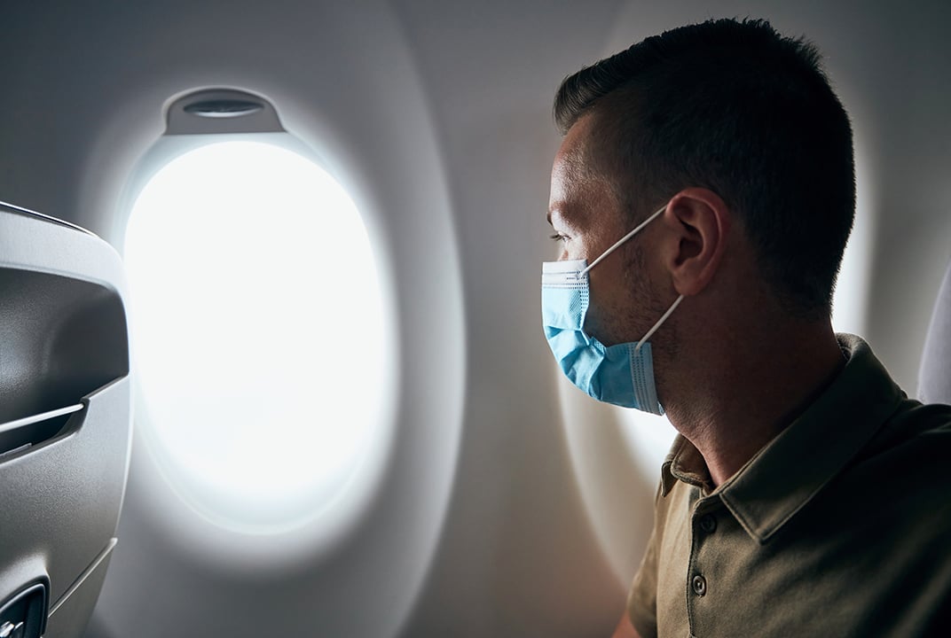 Man wearing face mask inside airplane during flight. Themes new normal, coronavirus and personal protection. ; Shutterstock ID 1793748502; Purchase Order: -