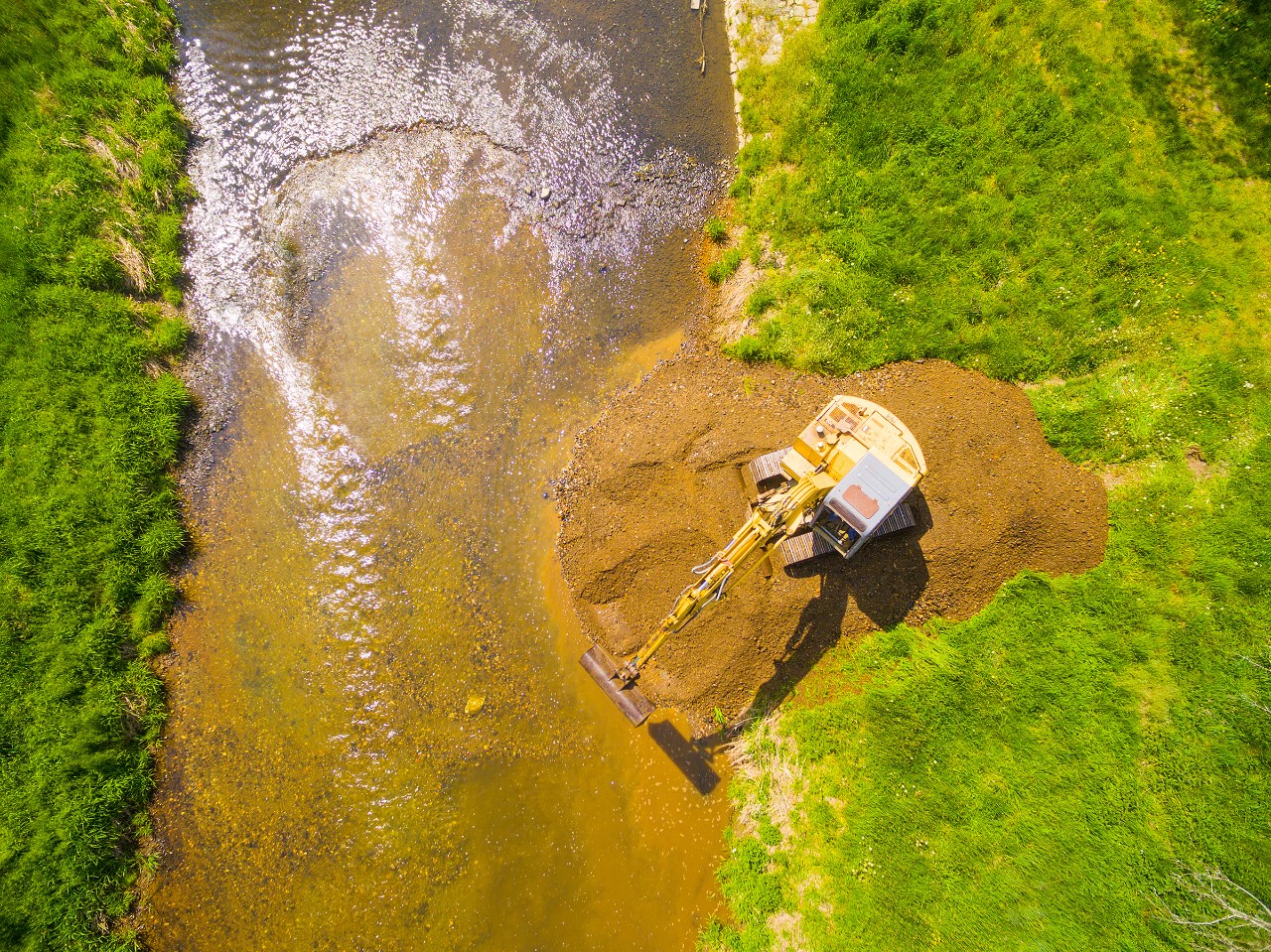 Looking down at an excavator mining alongside a river