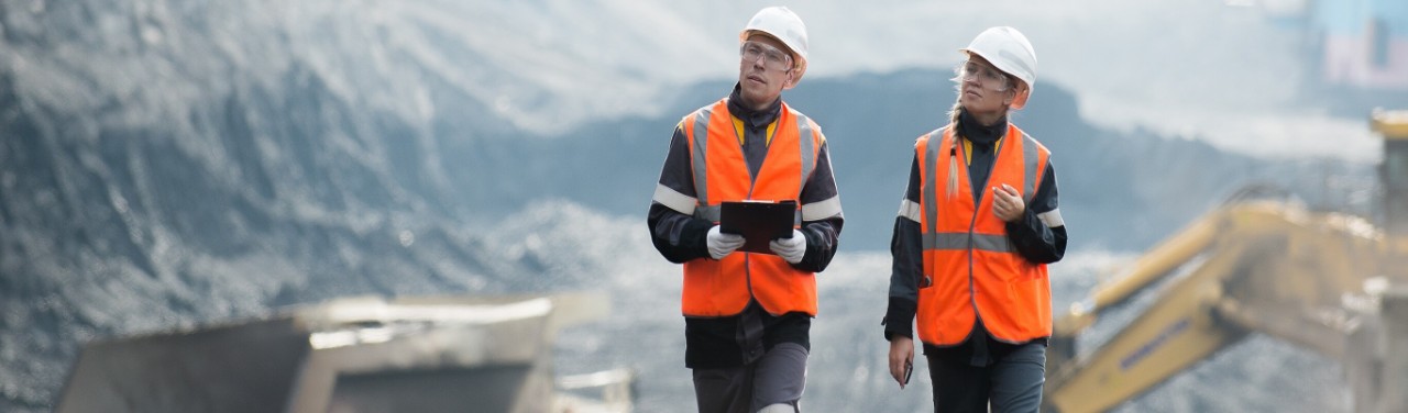 Hi-visibility vest wearing workers walking through an open case mine