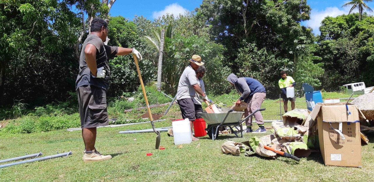 Construction of Automatic Weather Station on Niuatoputapu island, Tonga. Staff from the Tonga Meteorological Service and local construction company, Puloka Construction, mix concrete to pour into hand dug holes to secure the 10 m anemometer mast. With few construction resources on the island, all materials including pre-mixed concrete had to be transported with the installation team. (Jeremy Rutherford, NIWA)