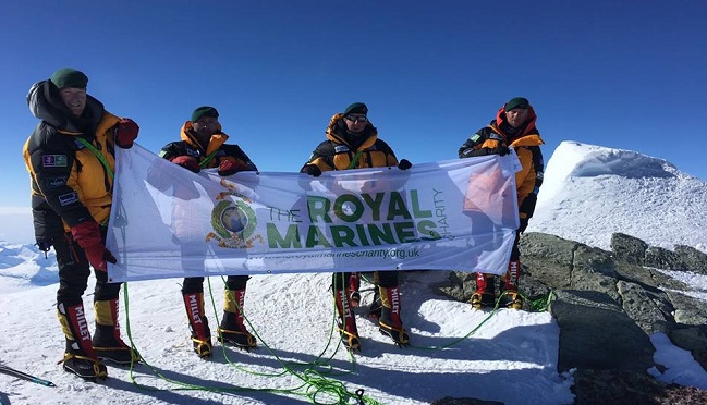 The 65 Degrees North exhibition team in Antarctica displaying the Roal Marines banner