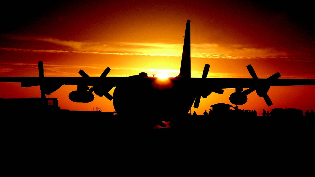 A C130 Hercules aircraft sat on the apron at sunset.