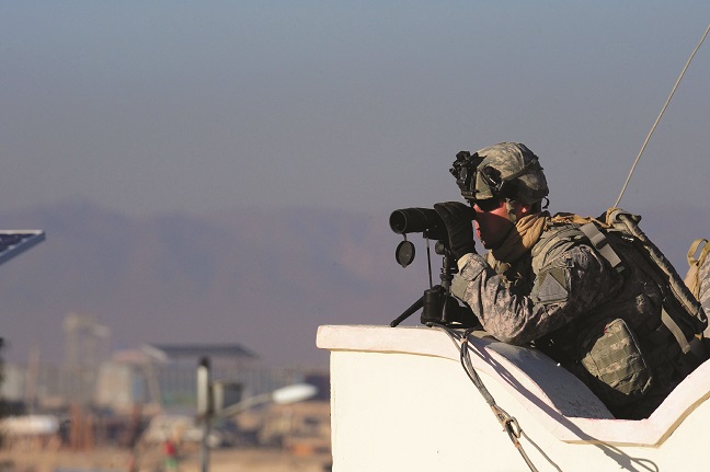 Member of military using binoculars to survey an area