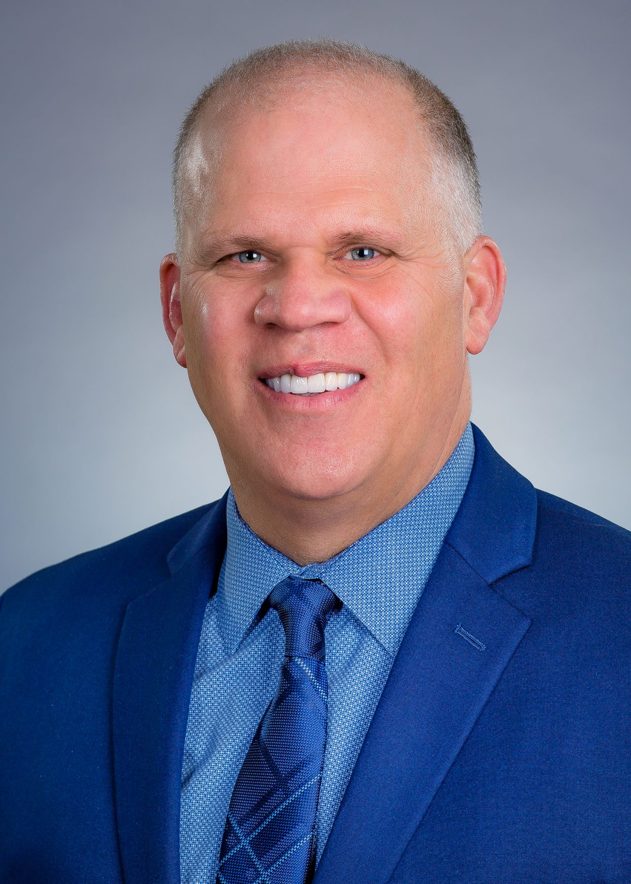 Head and shoulder photo of Inmarsat Government President Steve Gizinski in a blue suit jacket, blue shirt and blue tie