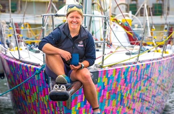 Lisa Blair holding a mug sat on the bow of her vessel