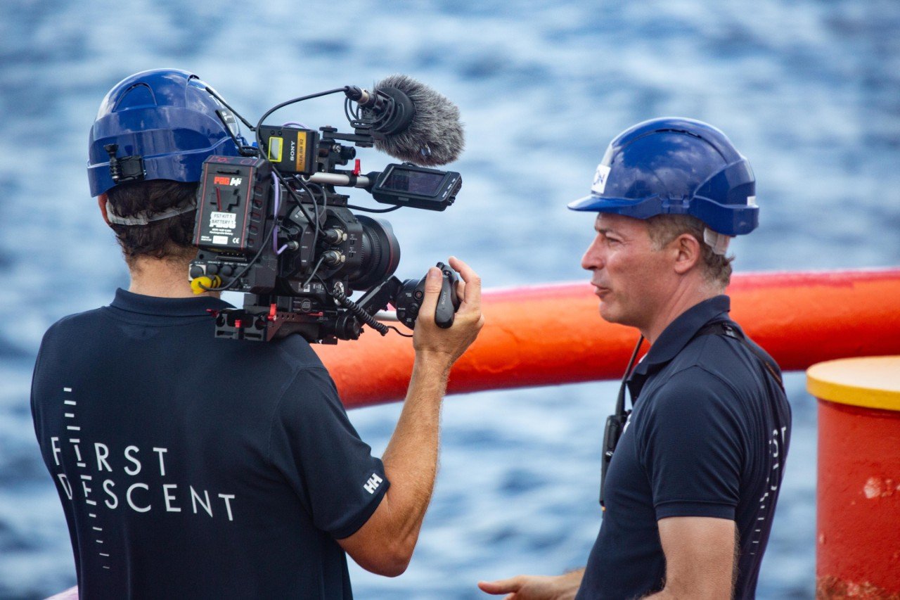 Leader of the expidtion being interviewed on camera aboard the First Descent vessell with the ocean in the background.