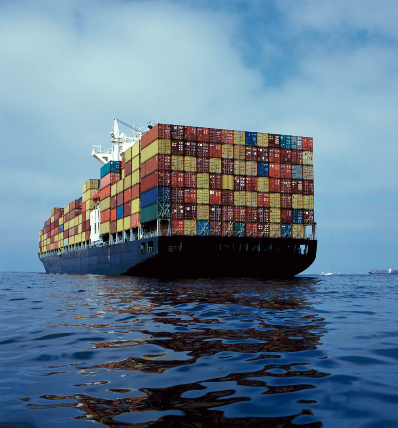 Merchant container vessel at sea carrying a large cargo of multi-coloured containers