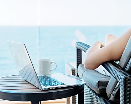 Yacht passenger relaxing in chair with a laptop on a table beside them
