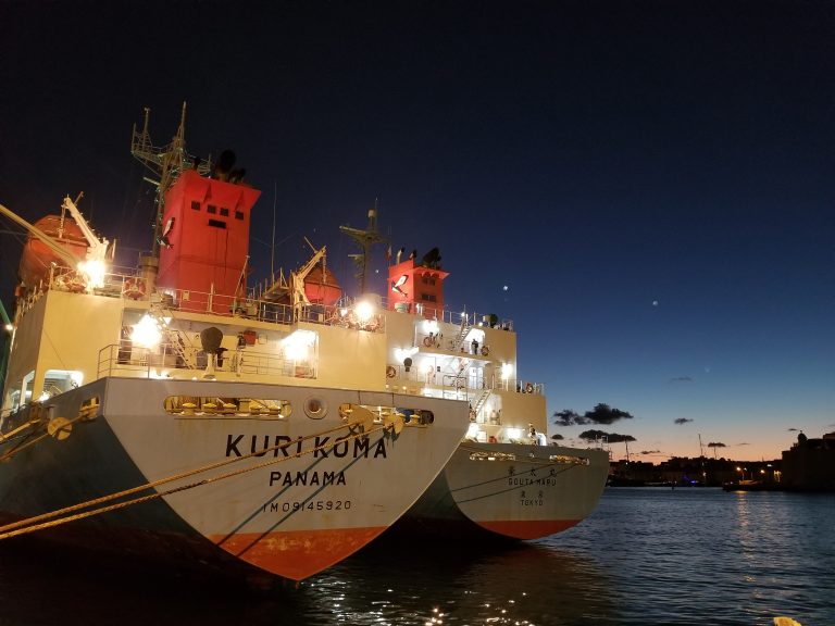 Fishing vessel named Kuri Koma anchored by the shore in the sunset