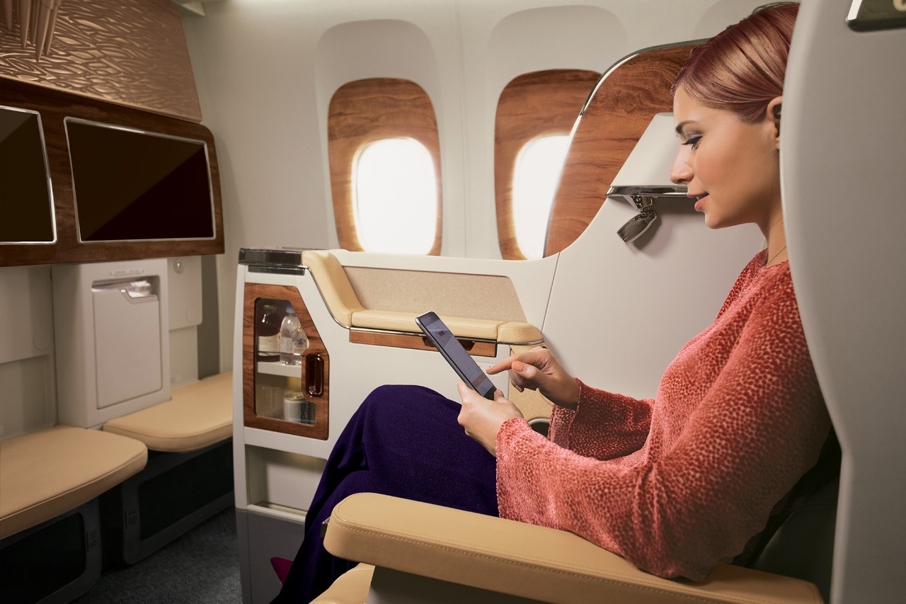 Emirates passenger in business class using phone