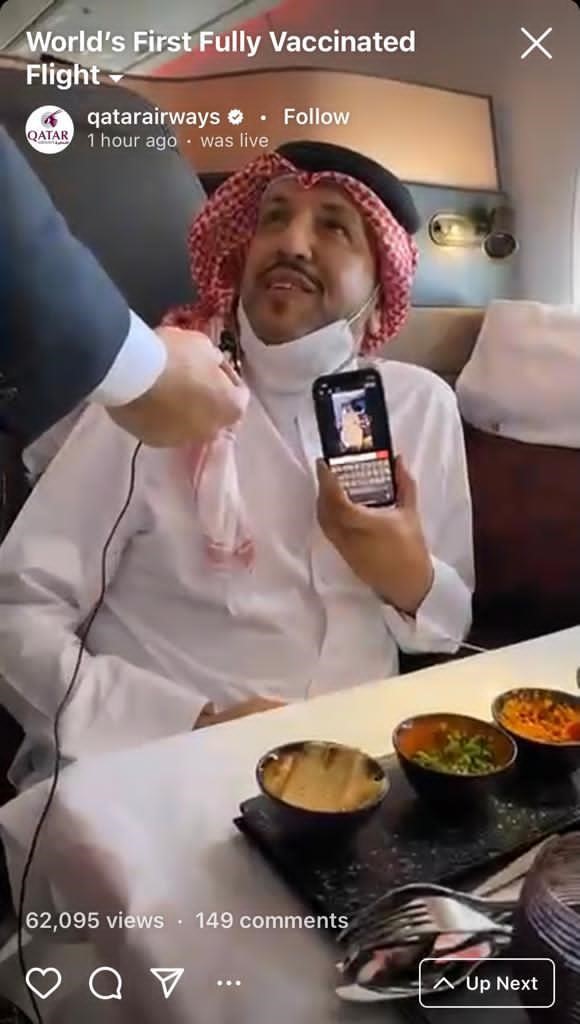 Qatari man seated on the Qatar Airways flight holding a mobile phone