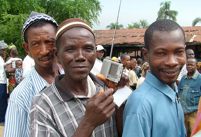 Sierra Leone residents listening to the radio at a voting centre