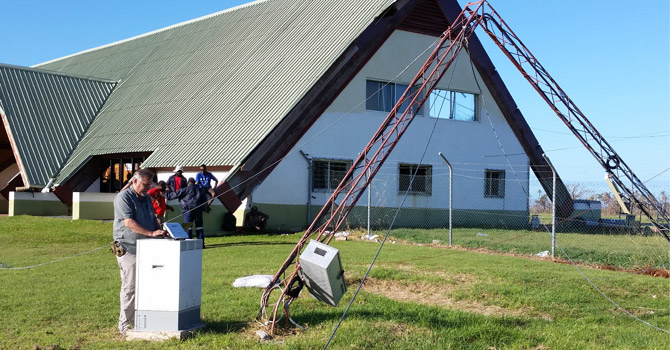 BGAN terminal being setup alongside a broken cell phone tower