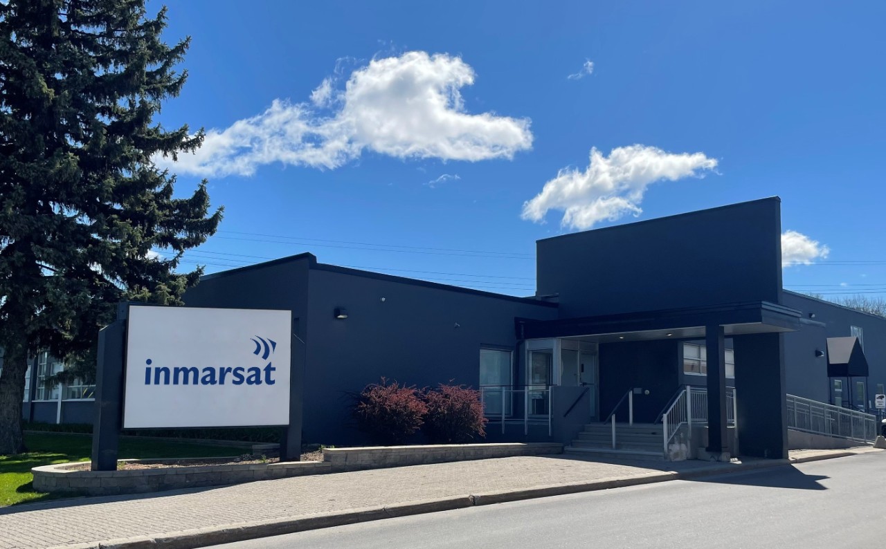 Low-level grey building with Inmarsat logo at the front, blue sky and a tree on the grounds