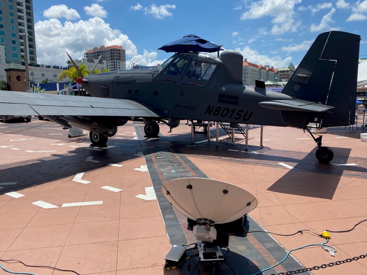 Stationary military plane on exhibit outside with a satellite dish in the foreground