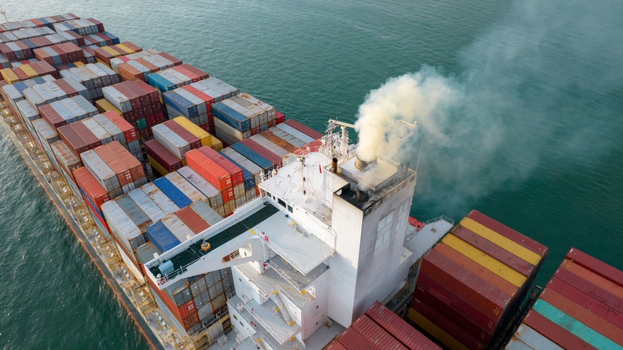 Merchant vessel emitting smoke from its stack.