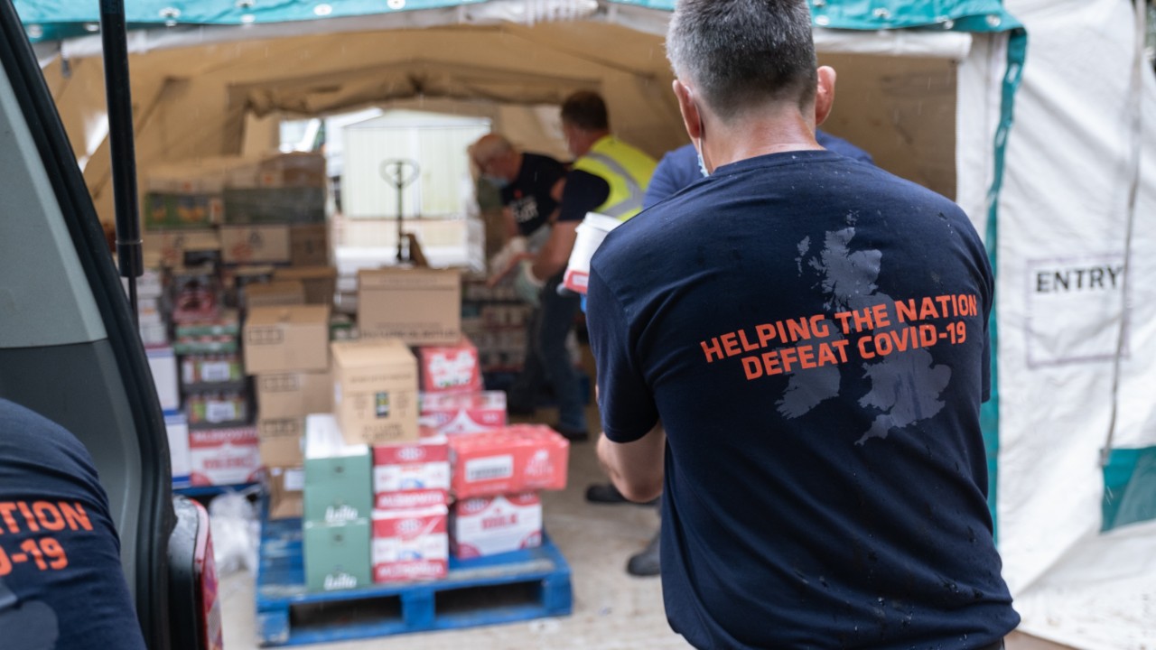 RE:ACT team in front of supplies in a tent