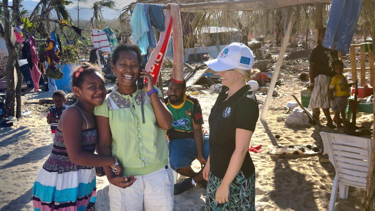 Local resident smiling whilst using a satellite phone provided by Télécoms Sans Frontières after a disaster